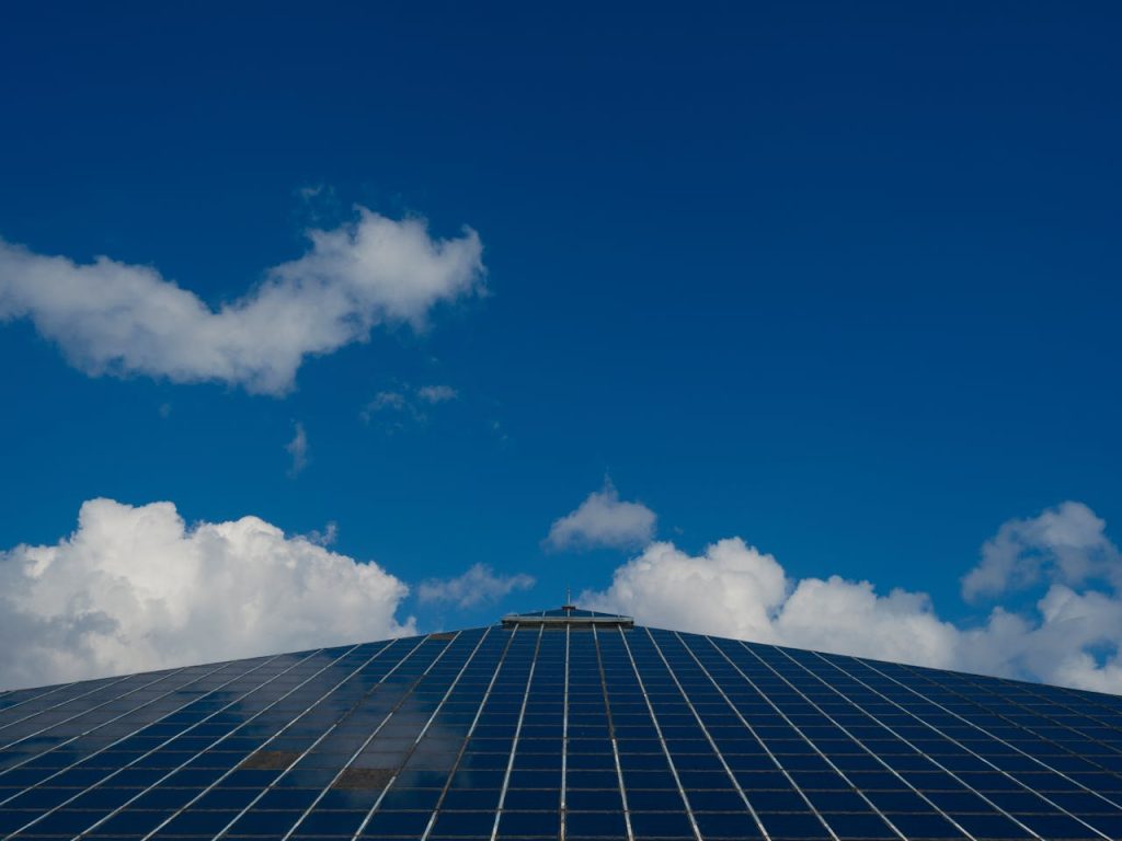 Solar panels reflecting a clear blue sky with scattered clouds, symbolizing renewable energy.